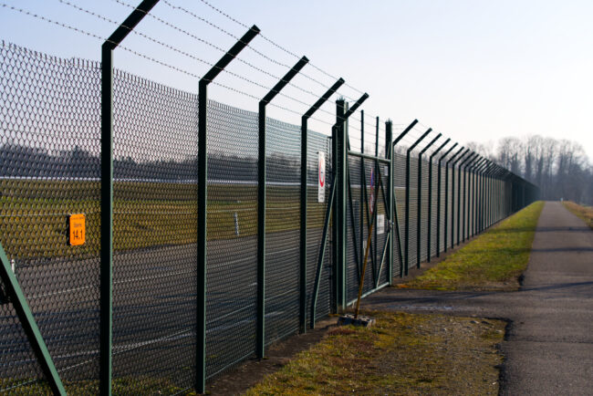 Rural landscape with fence of the airport in the background on a sunny winter day.
